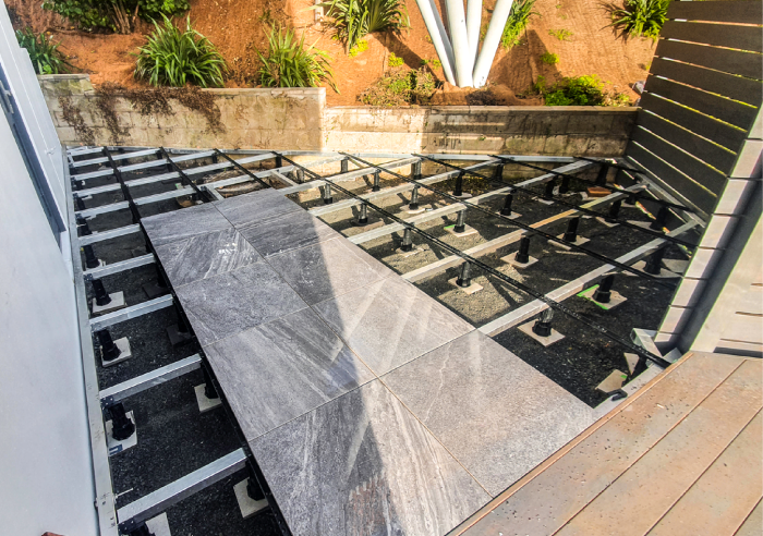 Anchorjak Aluminium Frame above compact metal, Creating a low maintenance permeable tiled entry way at the level of the inside for improved indoor outdoor flow.
